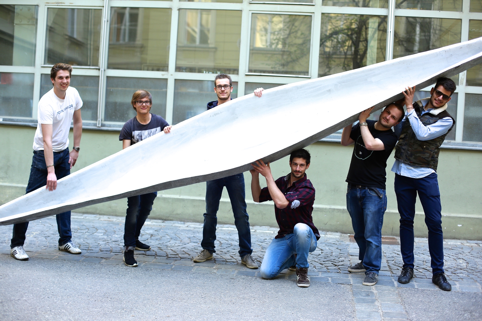 Six Students of the TU Graz Concrete Canu Team lift with an ultralight boat made of concrete.